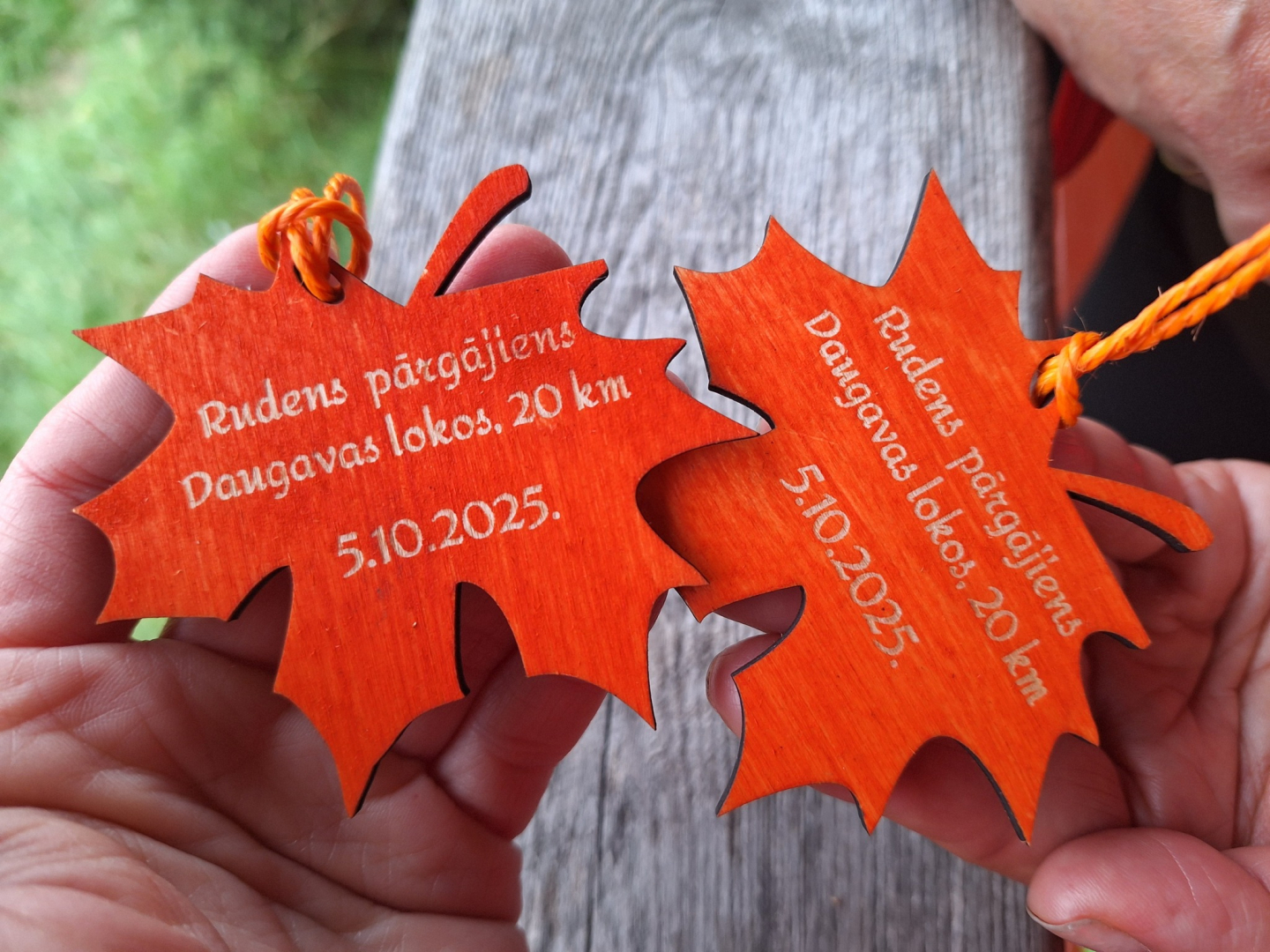 Divas koka lapiņu formas medaļas ar gravējumu “Rudens pārgājiens Daugavas lokos, 20 km, 5.10.2025.”