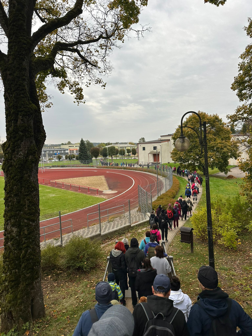 Liela cilvēku grupa dodas lejup pa kāpnēm gar stadionu, sākot pārgājienu