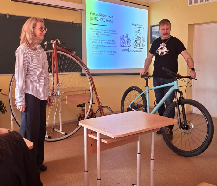 Klasē skolotāji demonstrē dažādus velosipēdus prezentācijas laikā.