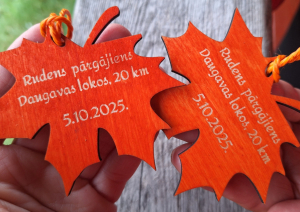 Divas koka lapiņu formas medaļas ar gravējumu “Rudens pārgājiens Daugavas lokos, 20 km, 5.10.2025.”