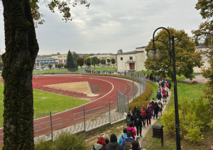 Liela cilvēku grupa dodas lejup pa kāpnēm gar stadionu, sākot pārgājienu