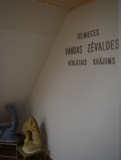 Piestiprināti burti uz sienas ar uzrakstu "Tēlnieces Vandas Zēvaldes atklātais krājums"