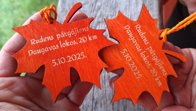 Divas koka lapiņu formas medaļas ar gravējumu “Rudens pārgājiens Daugavas lokos, 20 km, 5.10.2025.”