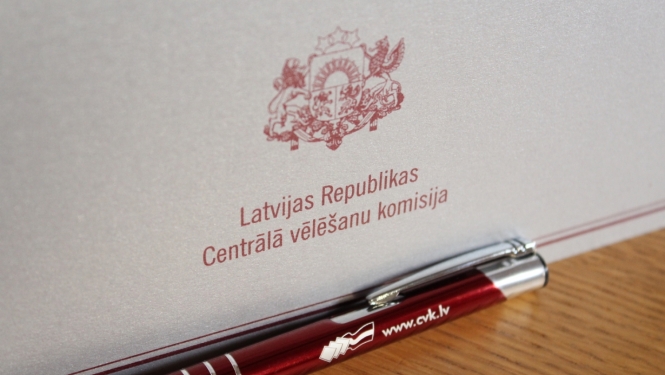 Šiltīte uz galda ar uzrakstu "Latvijas Republikas Centrālā vēlēšanu komisija" un valsts ģērboni