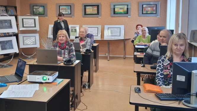 Cilvēki sēž pie galdiem ar datoriem