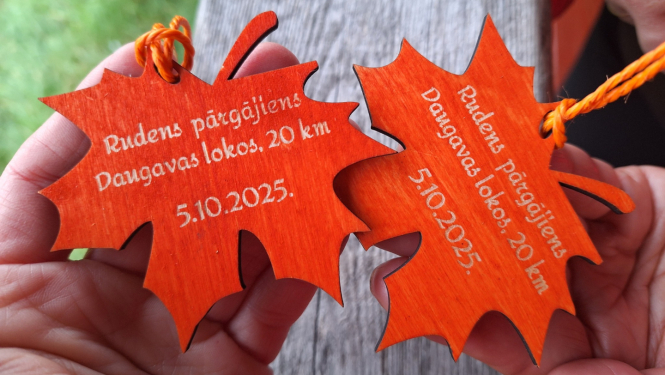 Divas koka lapiņu formas medaļas ar gravējumu “Rudens pārgājiens Daugavas lokos, 20 km, 5.10.2025.”
