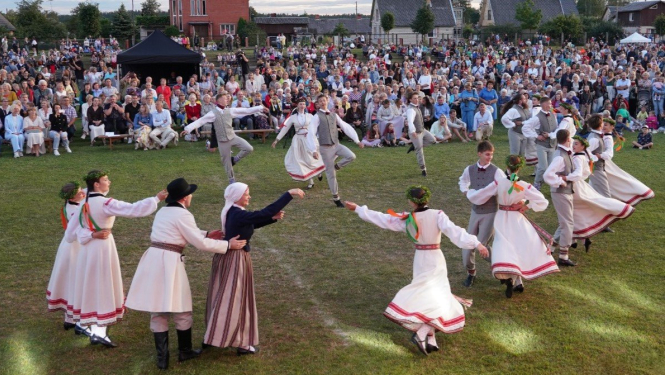 Dejotāji tautastērpos dejo laukā skatītāju pūļa priekšā