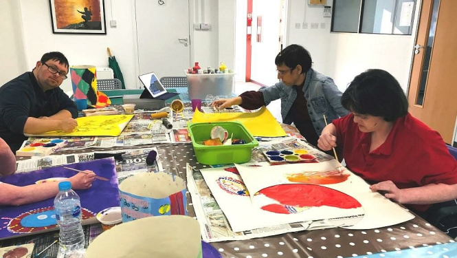 Četras personas ar invaliditāti pie galda glezno