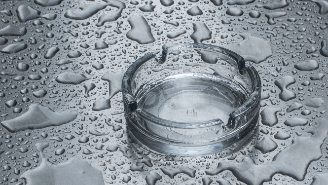 Tukšs pelnu trauks ar ūdens pilieniem apkārt tam