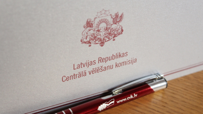 Šiltīte uz galda ar uzrakstu "Latvijas Republikas Centrālā vēlēšanu komisija" un valsts ģērboni
