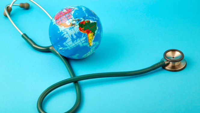 Stetoskops un neliels globuss guļ uz zila fona