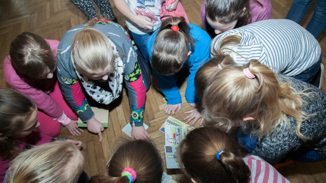Bērni uz grīdas spēlē izglītojošu spēli