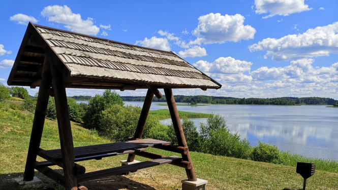 Koka galds ar jumtu ezera krastā