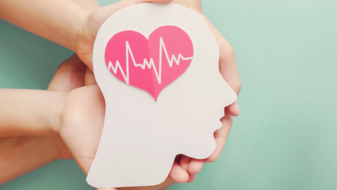 Trīs cilvēku rokas tur no kartona izgrieztu galvas kontūru ar no papīra izgrieztu sirdi uz tās.