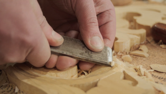 Vīrietis ar kaltu apstrādā koku