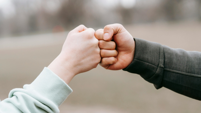 Divi cilvēki izrāda atbalsta zīmi - saskaras ar dūrēm