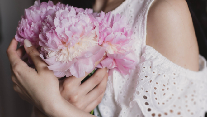 Sieviete piespieda ziedus sev pie krūtīm