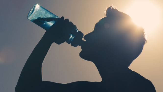 Vīrietis (siluets) dzer ūdeni no ūdens pudeles
