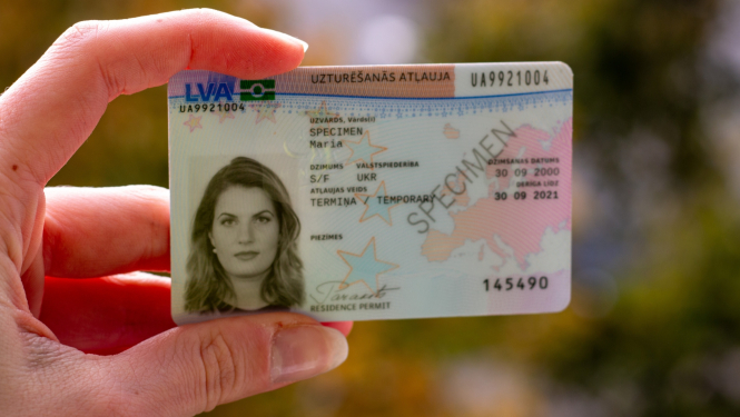 Cilvēks tur rokā termiņa uzturēšanās atļauju