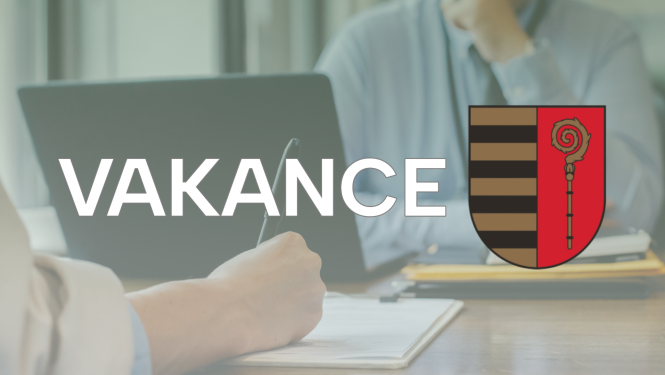 Uzraksts "VAKANCE" un Krāslavas novada ģērbonis uz procesā notiekošās darba intervijas fona