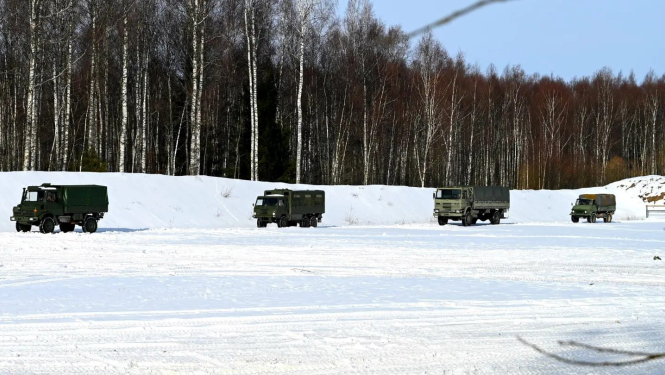 Zemessardzes autotransporta konvojs brauc pa ceļu ziemā