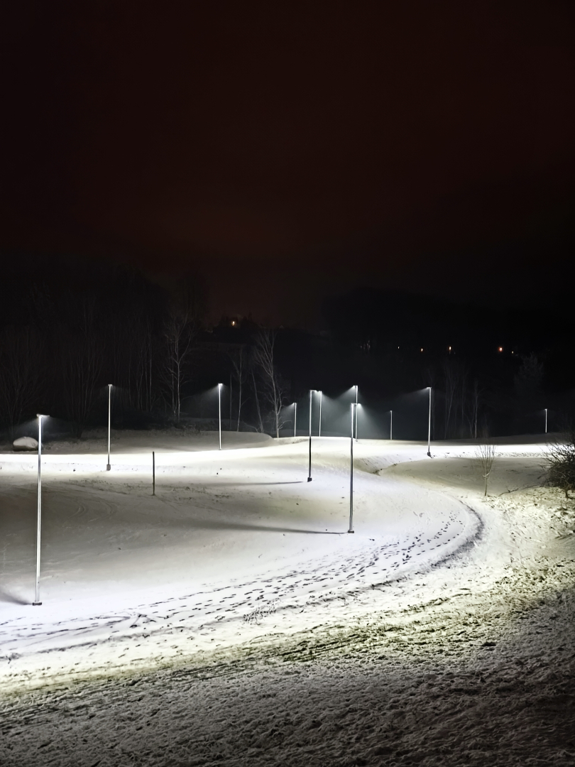 Apgaismots, sniegots stadions rindā izvietotiem laternu stabiem