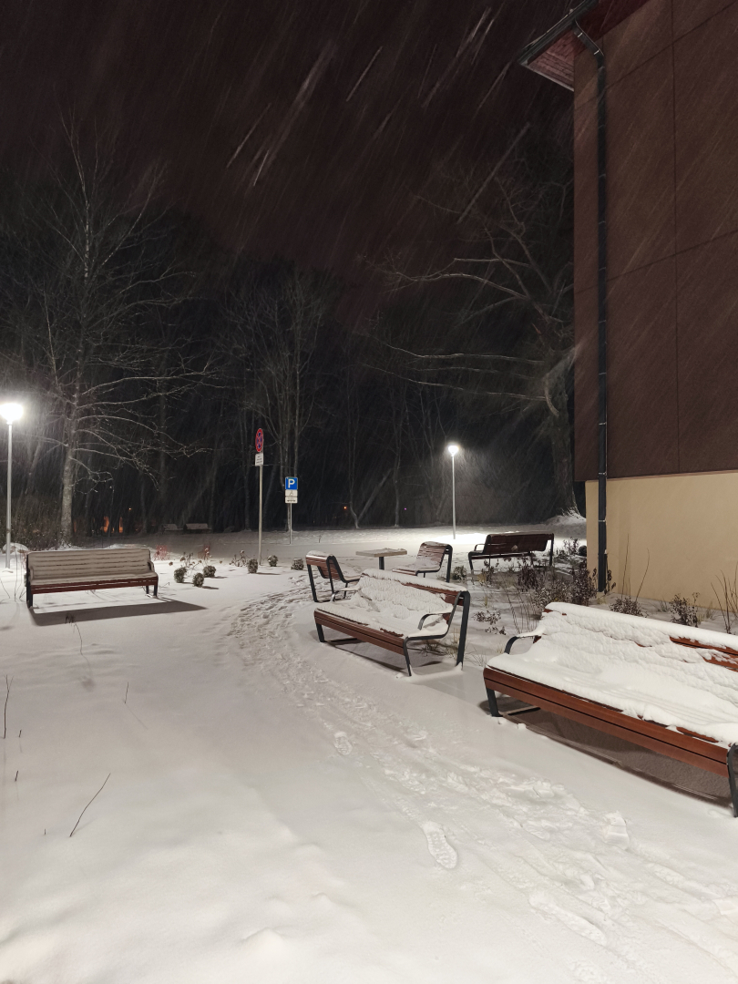 Sniegots pagalms ar soliem un ēkas sienu