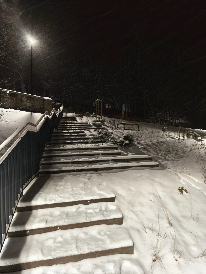 Sniegotas āra kāpnes naktī ar laternu augšpusē