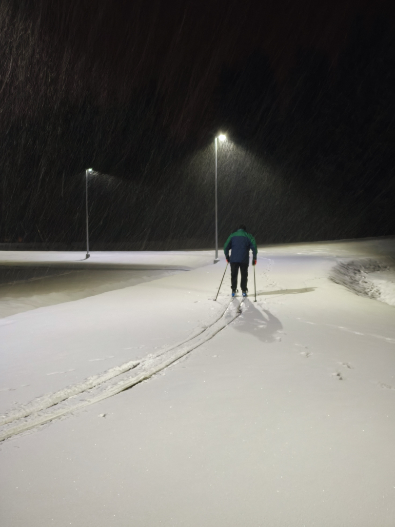 Cilvēks uz slēpēm dodas pa svaigu sniegu stadionā