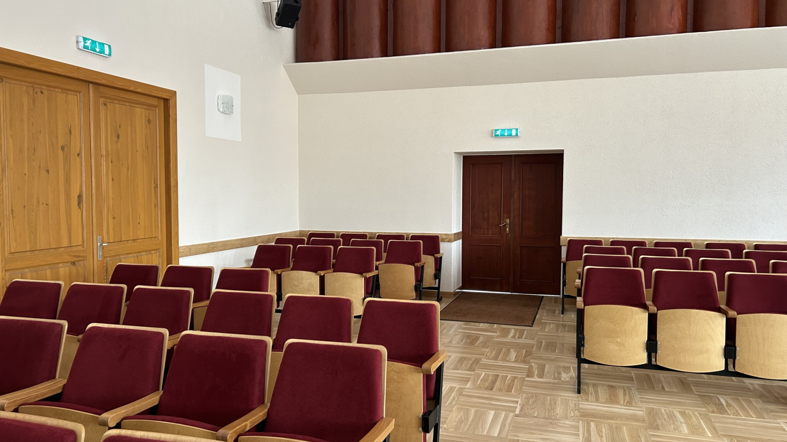 Krēslu rindas zālē un durvis aizmugurē.