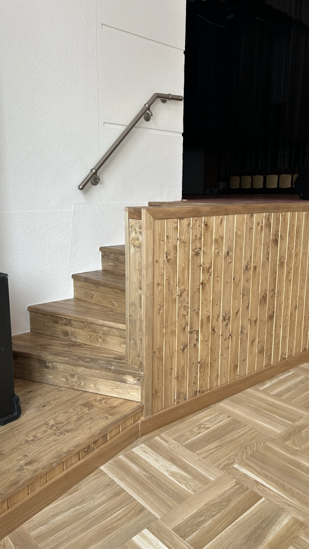 Zāle ar krēsliem un skatuvi sānskatā.