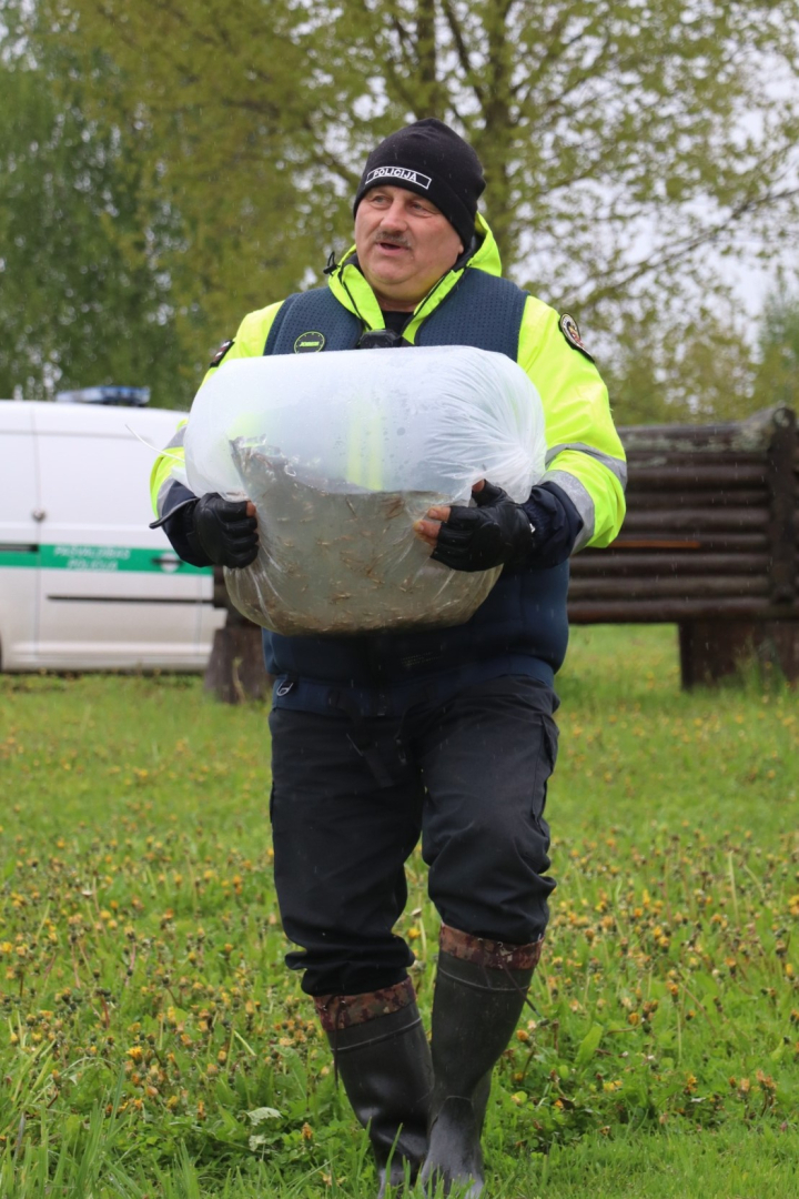 Vīrietis nes lielu plastmasas maisu ar zivju mazuļiem
