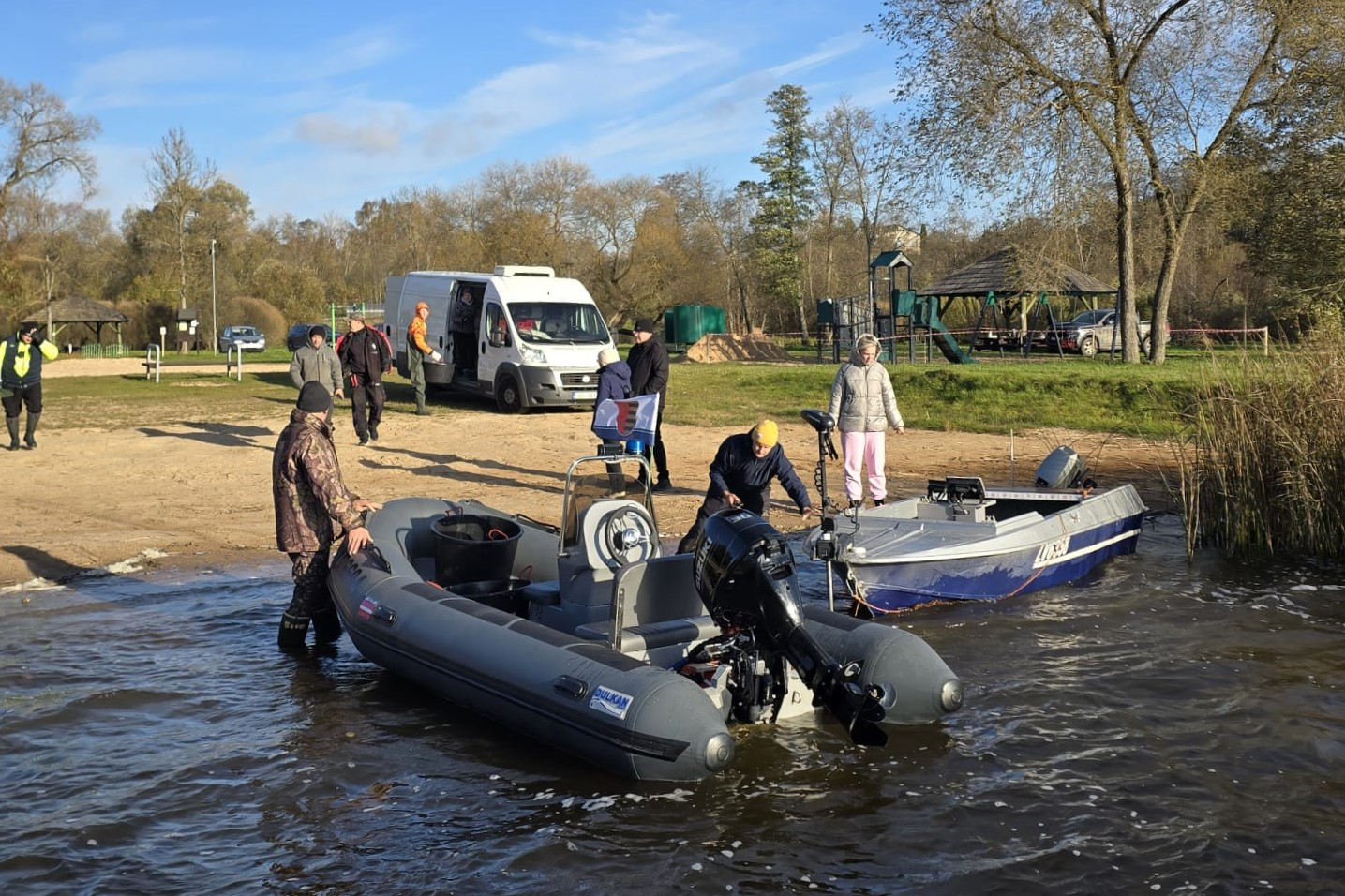 Cilvēki pie ezera gatavo laivas