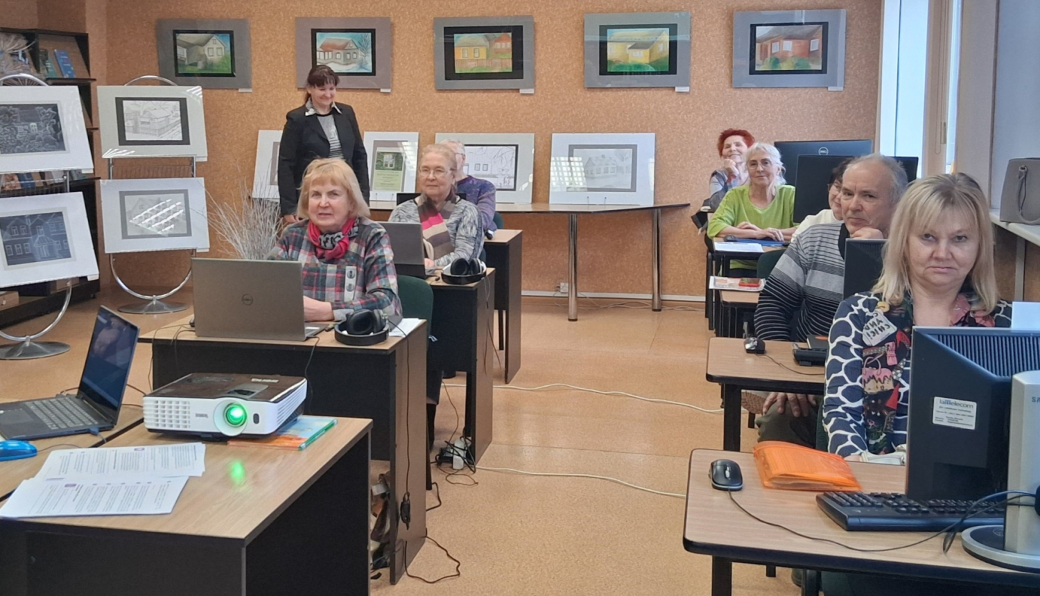 Cilvēki sēž pie galdiem ar datoriem