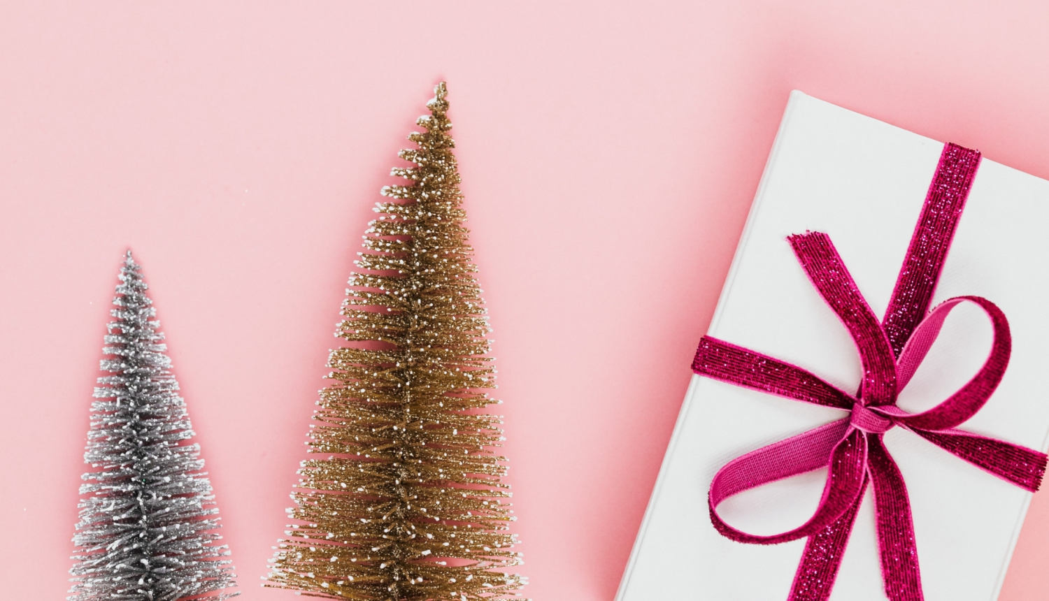 Divas mazas, mākslīgas eglītes un dāvana uz rozā fona