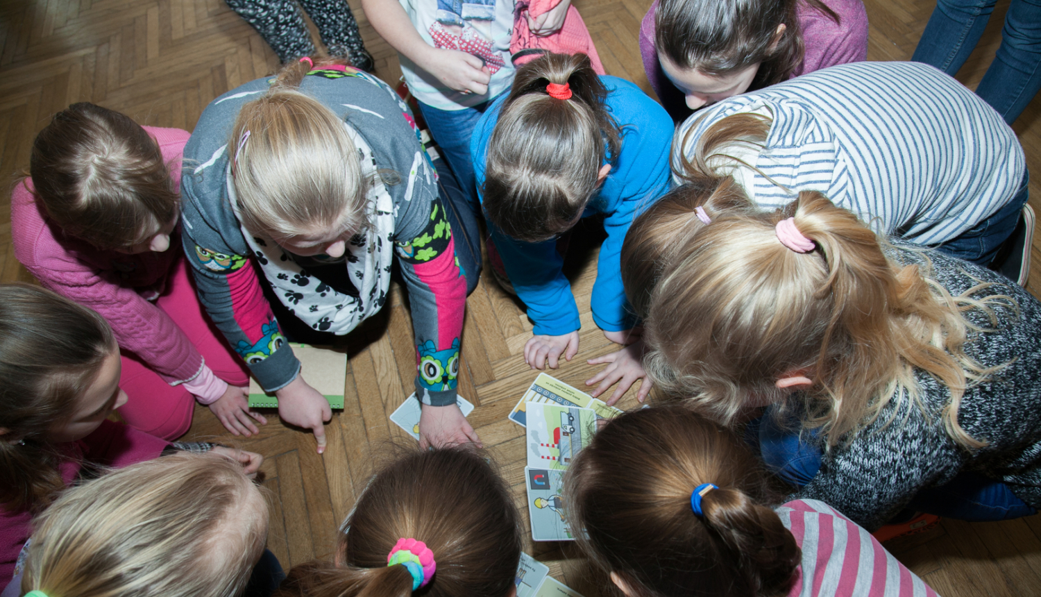 Bērni uz grīdas spēlē izglītojošu spēli