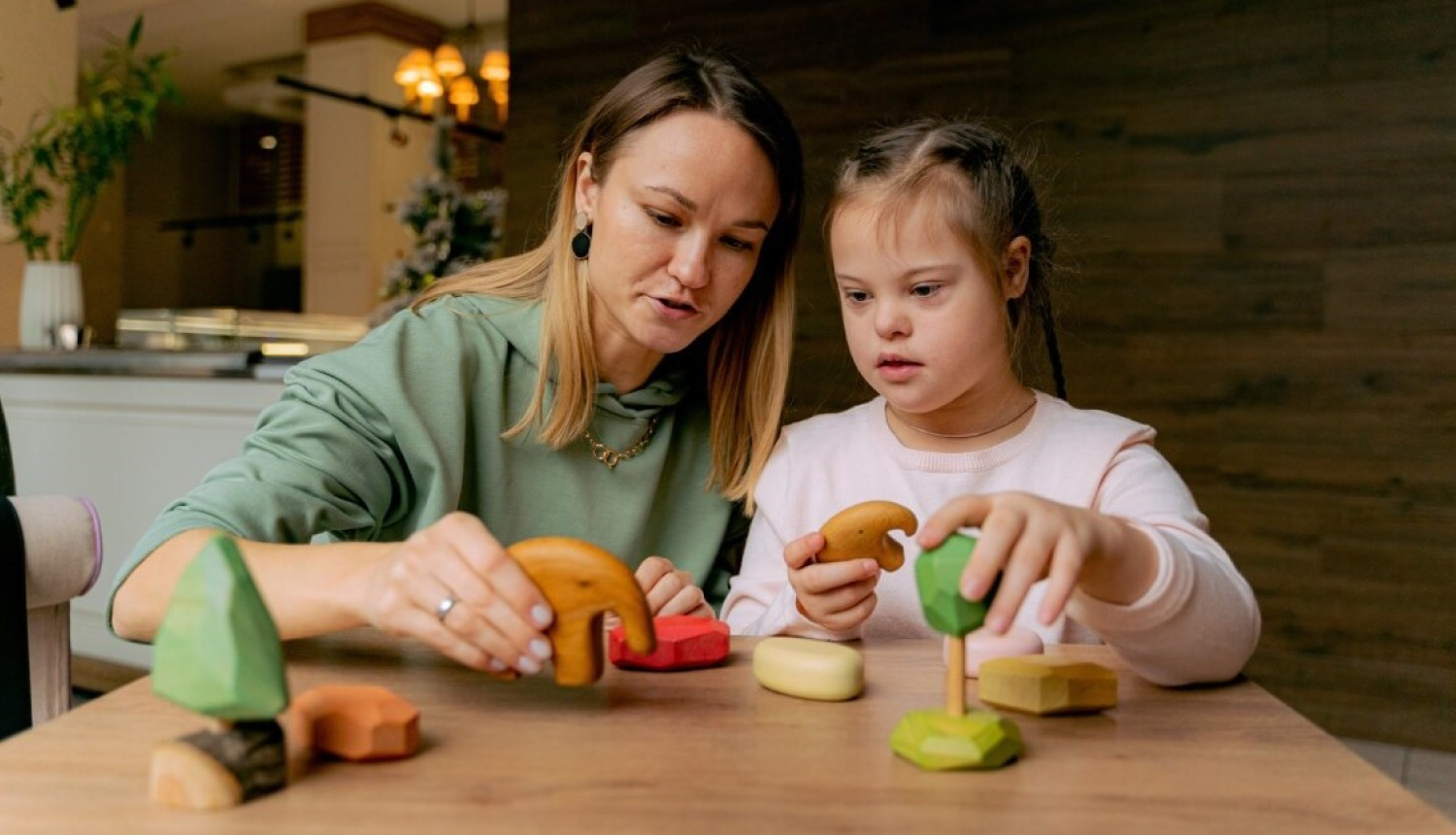Sieviete spēlējas ar meiteni ar Dauna sindromu
