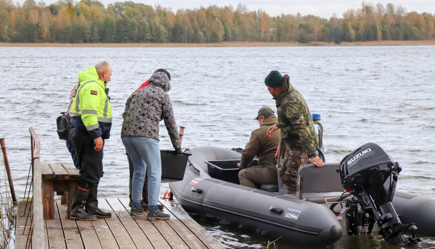 PVD, VVD un pašvaldības policijas darbinieki ieliek kastes ar zivju mazuļiem laivā