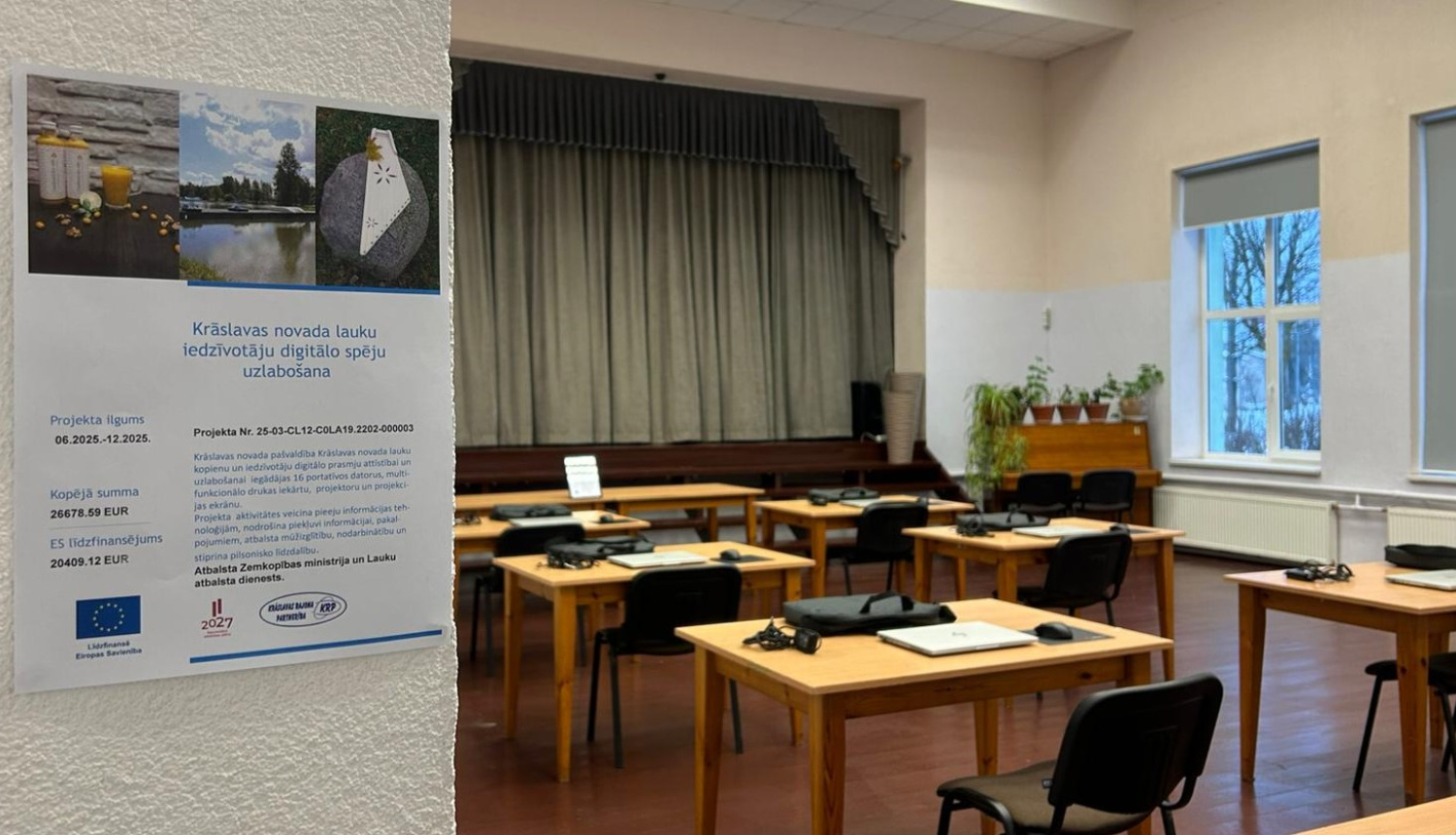 Mācību telpa ar vairākiem galdiem un krēsliem, uz galdiem novietoti portatīvie datori