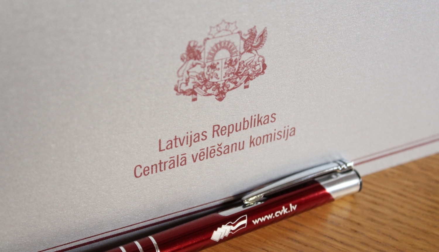 Šiltīte uz galda ar uzrakstu "Latvijas Republikas Centrālā vēlēšanu komisija" un valsts ģērboni