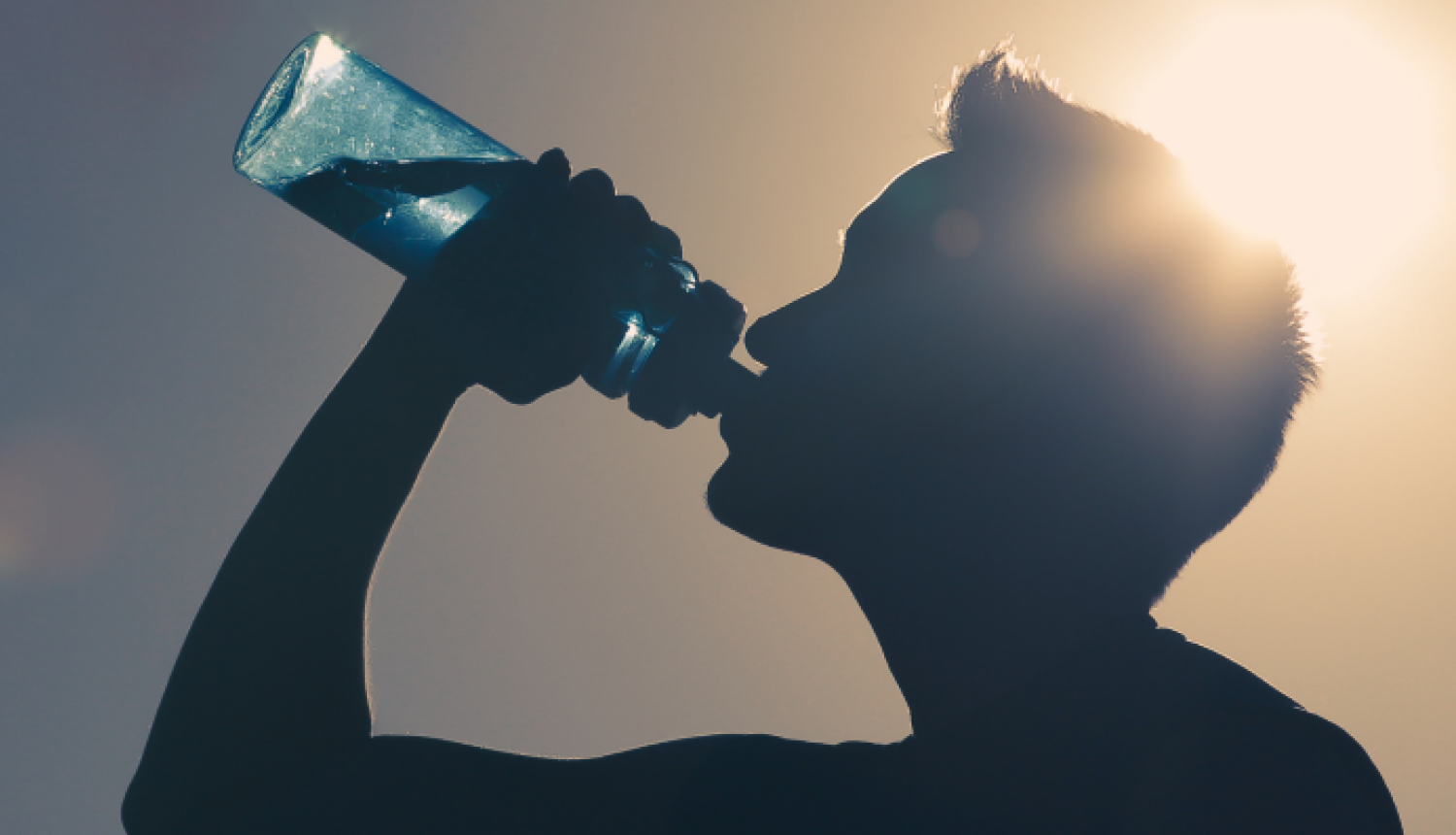 Vīrietis (siluets) dzer ūdeni no ūdens pudeles